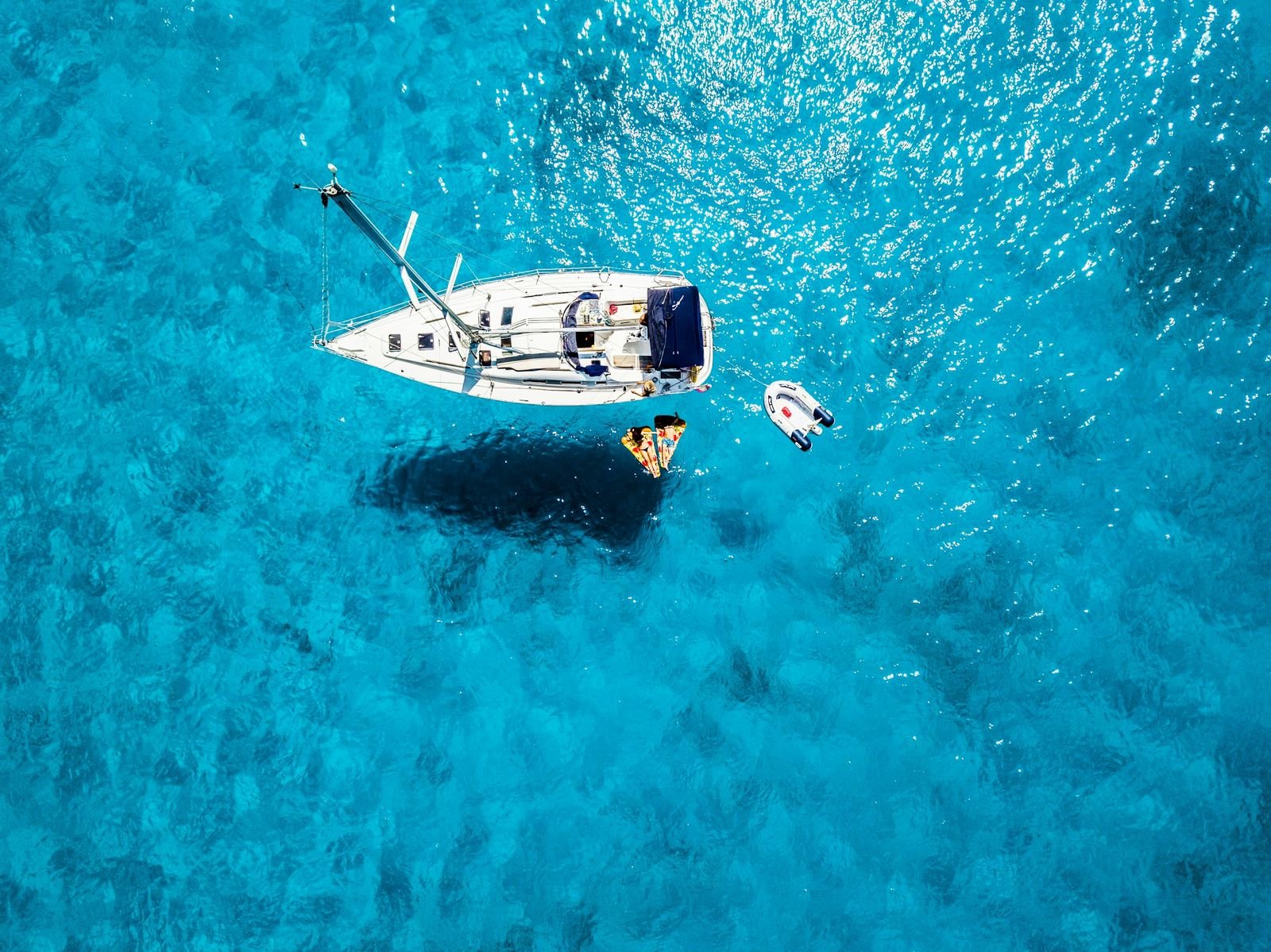 A sailing yacht in turquoise Mediterranean water, seen from above