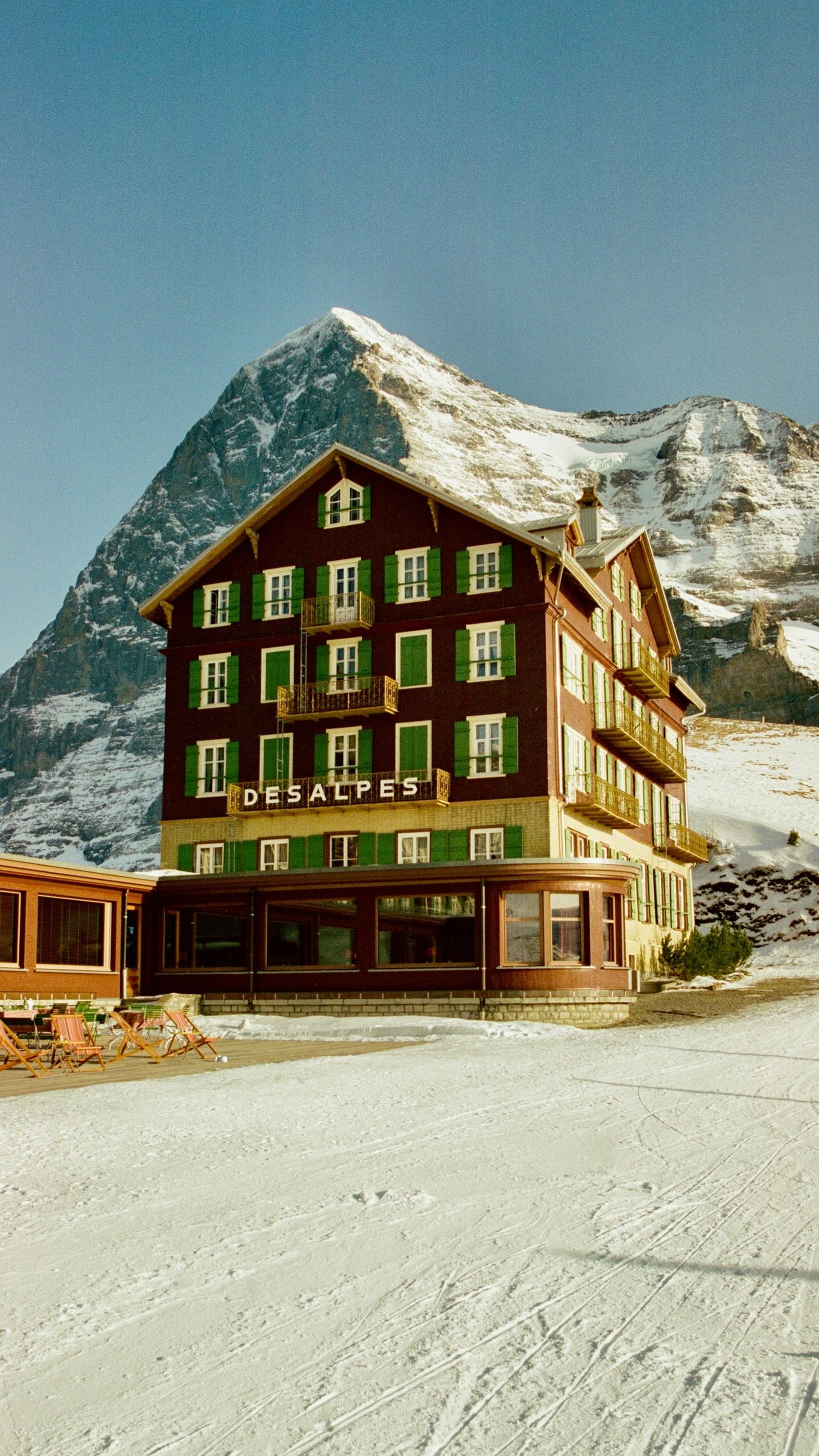 A historic Alpine hotel below a snow-capped peak
